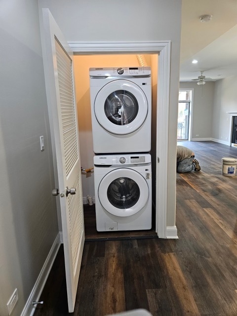 laundry area featuring stacked washer and dryer, dark hardwood / wood-style floors, and ceiling fan