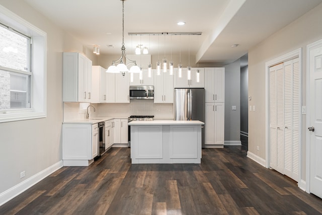 kitchen with a center island, backsplash, white cabinets, decorative light fixtures, and stainless steel appliances