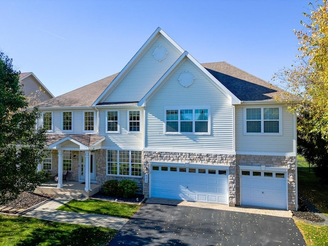 view of front of property featuring driveway, stone siding, roof with shingles, and an attached garage