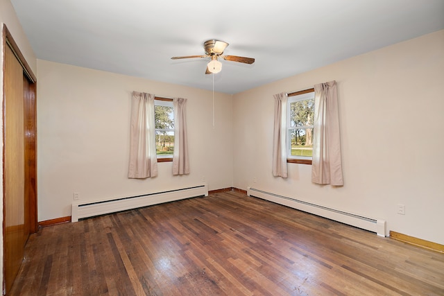 spare room featuring wood-type flooring, baseboard heating, and a healthy amount of sunlight