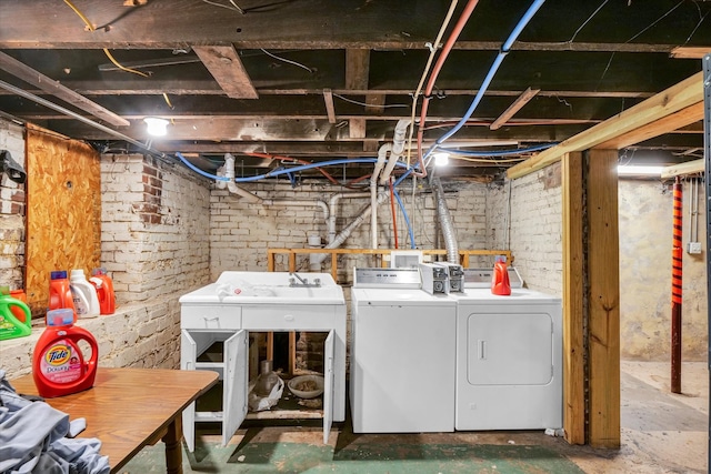 laundry area with brick wall and washing machine and dryer