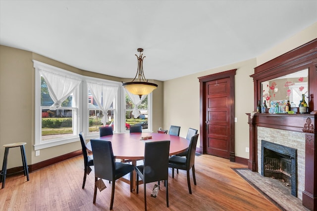 dining space featuring light wood-type flooring and a fireplace