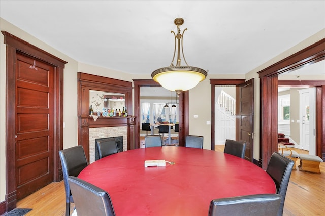 dining space featuring a stone fireplace and light wood-type flooring