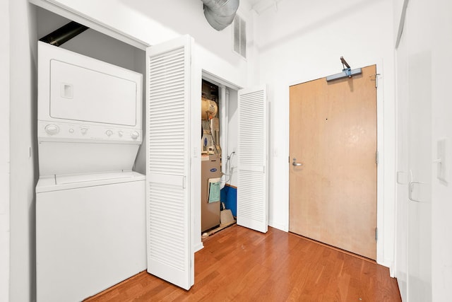 washroom with wood-type flooring and stacked washer and dryer