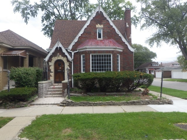tudor home featuring brick siding and a chimney