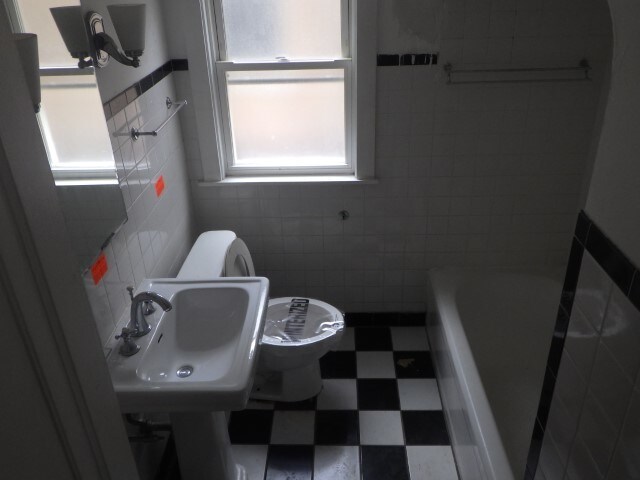 bathroom with tile walls, sink, a tub, and toilet