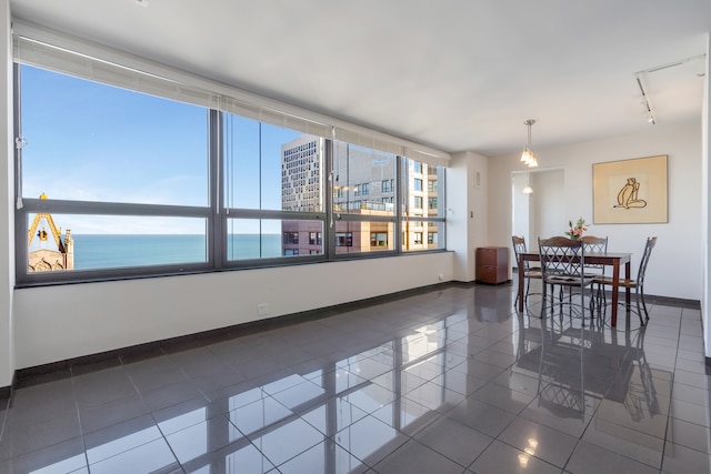 tiled dining room with a water view and track lighting