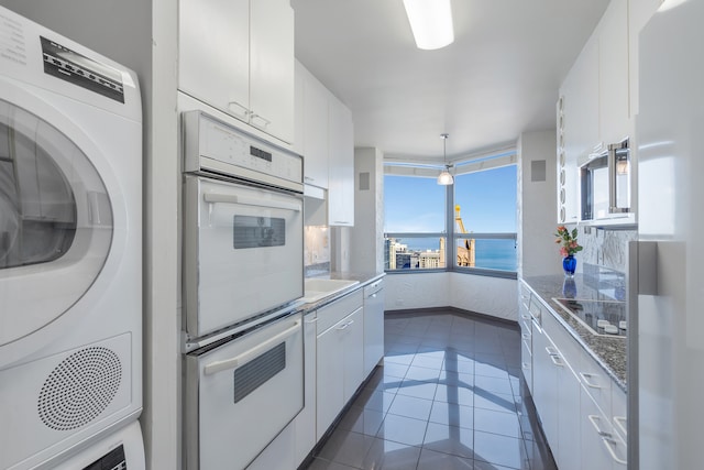 kitchen with electric cooktop, a water view, pendant lighting, and white cabinets