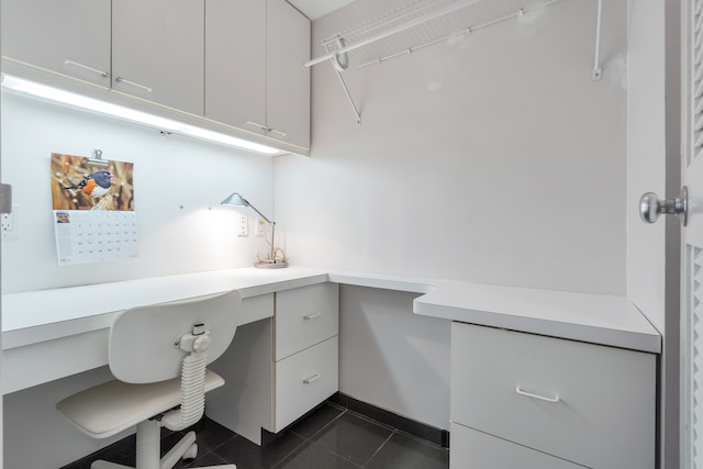 office area with dark tile patterned floors and built in desk