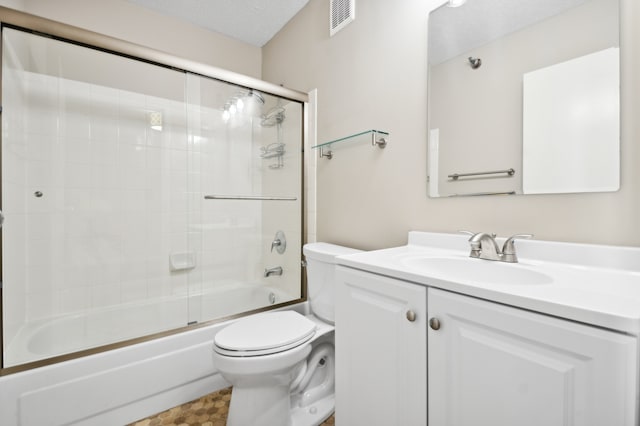 full bathroom featuring a textured ceiling, shower / bath combination with glass door, toilet, and vanity