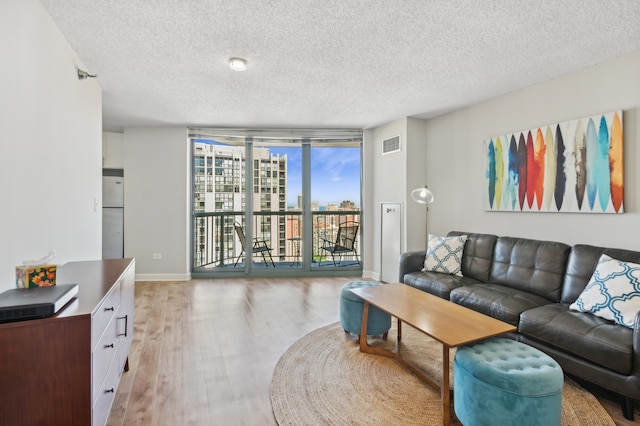 living room with light wood-type flooring, a textured ceiling, and floor to ceiling windows