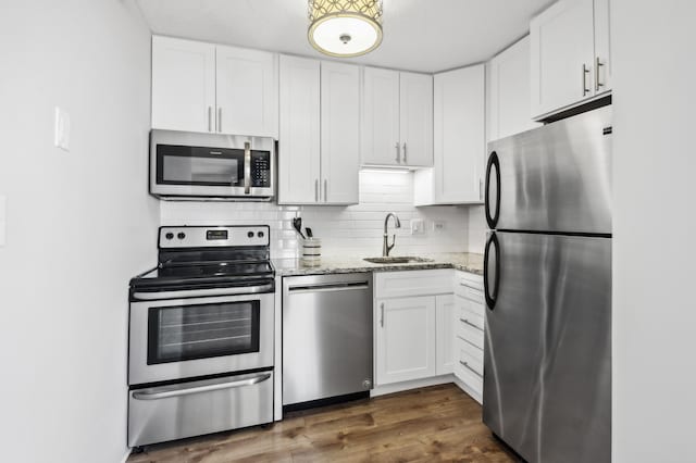 kitchen featuring light stone counters, dark wood-type flooring, sink, white cabinets, and appliances with stainless steel finishes