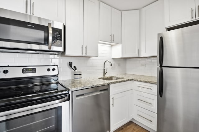 kitchen featuring white cabinets, appliances with stainless steel finishes, tasteful backsplash, and sink