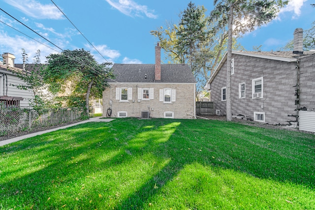 rear view of house with central AC unit and a lawn