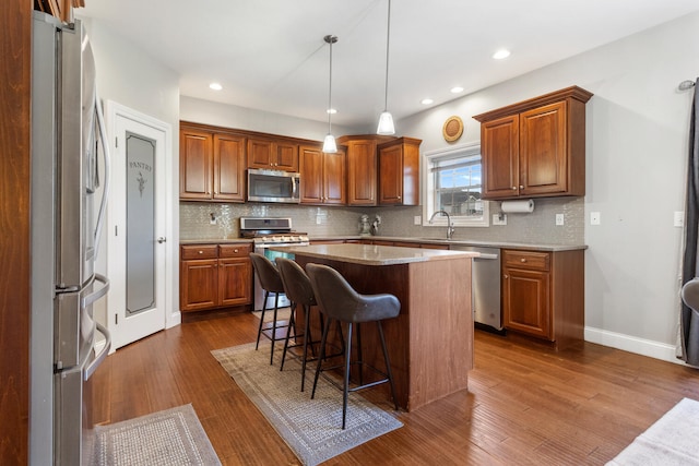 kitchen with pendant lighting, a center island, stainless steel appliances, backsplash, and dark hardwood / wood-style flooring