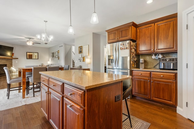 kitchen with light stone countertops, decorative light fixtures, dark hardwood / wood-style flooring, and a center island