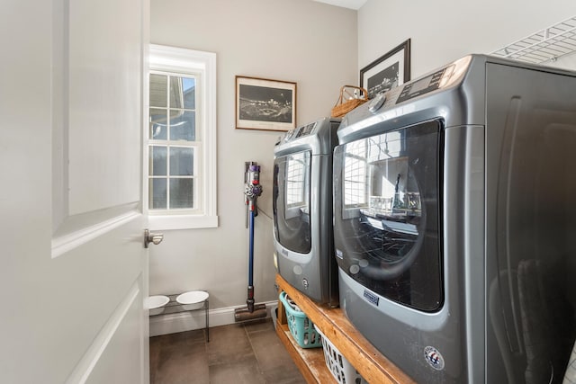 clothes washing area with dark tile patterned flooring, washer / dryer, and plenty of natural light