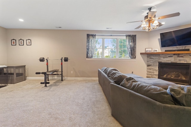 living room featuring a fireplace, ceiling fan, and light carpet