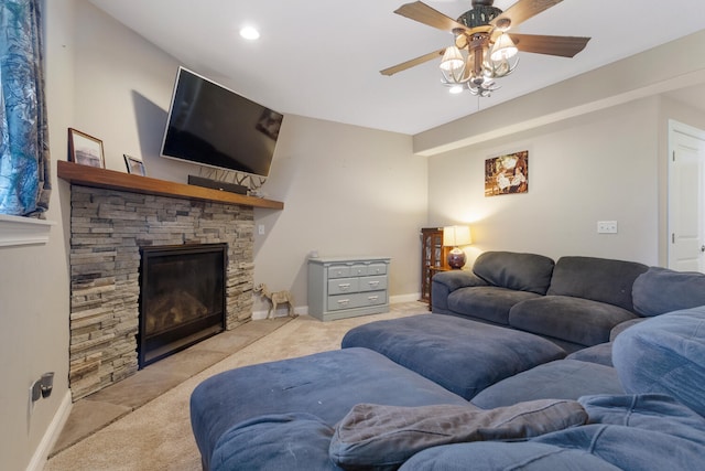 carpeted living room with ceiling fan and a stone fireplace