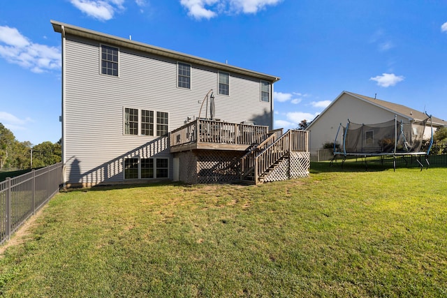 back of house with a lawn, a trampoline, and a deck