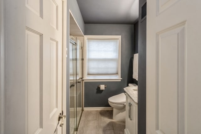 bathroom with a shower with shower door, vanity, toilet, and tile patterned floors