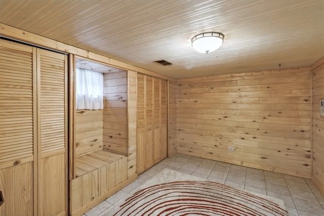 unfurnished bedroom with wooden walls and light tile patterned floors