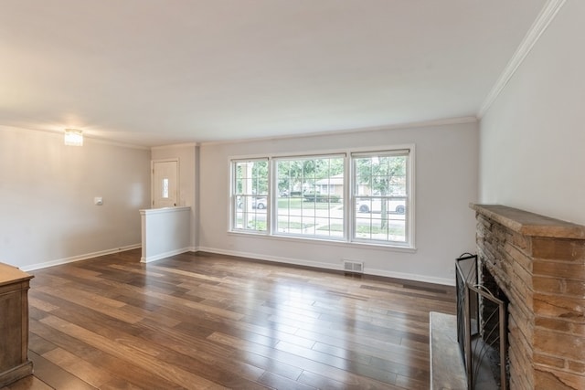 unfurnished living room featuring ornamental molding, dark hardwood / wood-style floors, and a stone fireplace