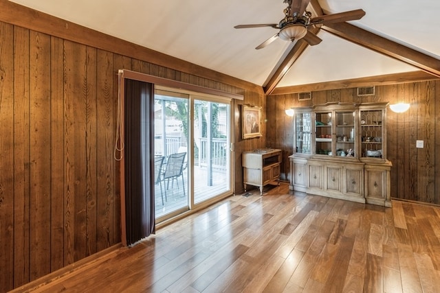 interior space featuring wooden walls, vaulted ceiling with beams, and ceiling fan