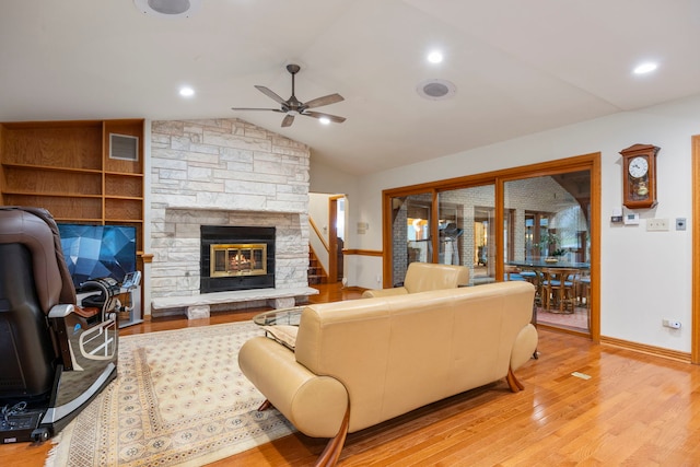 living room featuring vaulted ceiling, ceiling fan, built in features, a fireplace, and light hardwood / wood-style floors