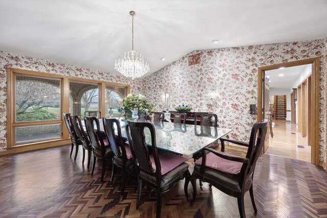 dining space featuring dark parquet flooring, lofted ceiling, and an inviting chandelier