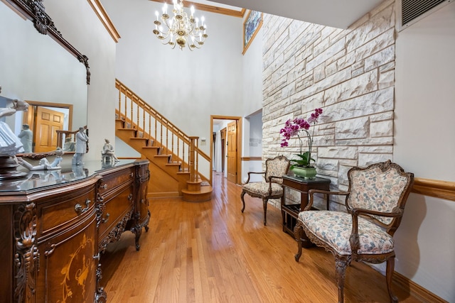 entryway featuring a notable chandelier, light hardwood / wood-style floors, a towering ceiling, and crown molding