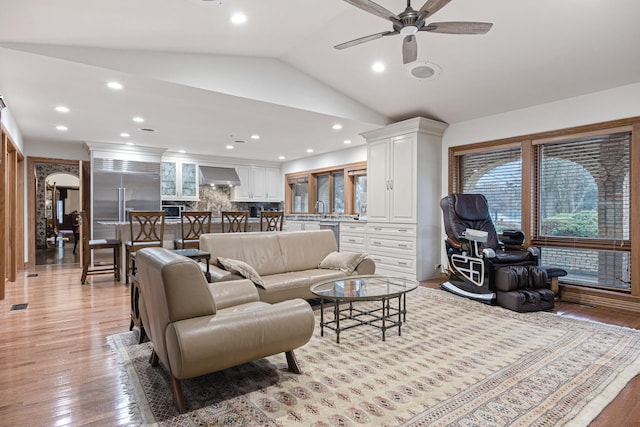 living room with ceiling fan, light wood-type flooring, and lofted ceiling