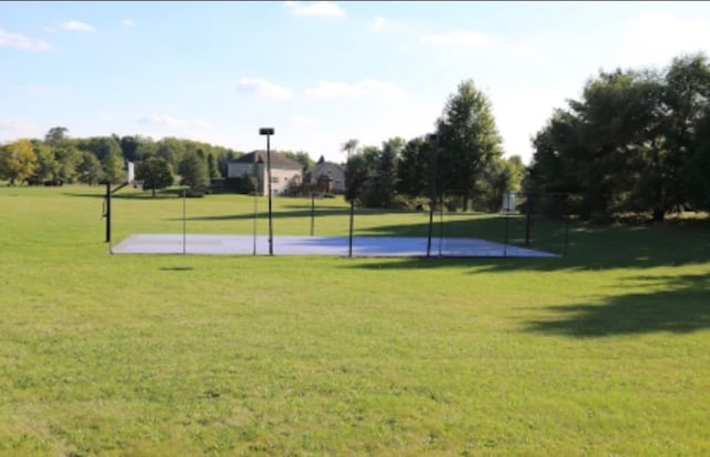 view of sport court featuring a lawn