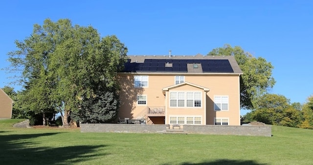 rear view of house featuring solar panels and a yard