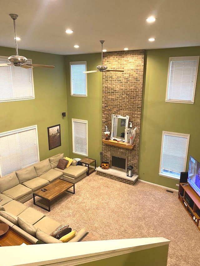 living room featuring ceiling fan, a fireplace, and carpet