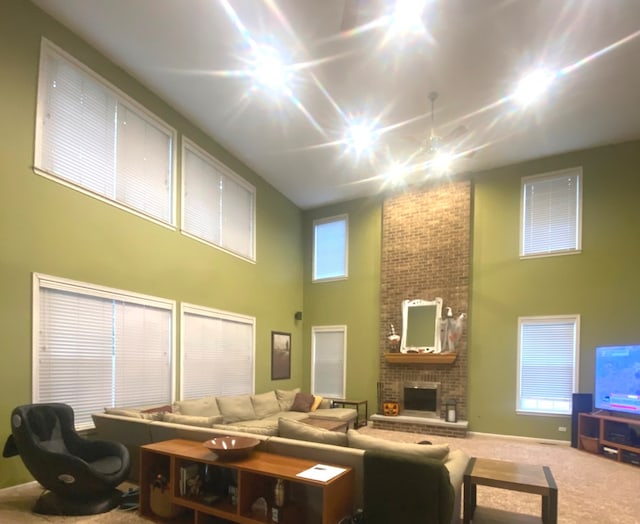 living room featuring carpet floors, a brick fireplace, a high ceiling, and ceiling fan