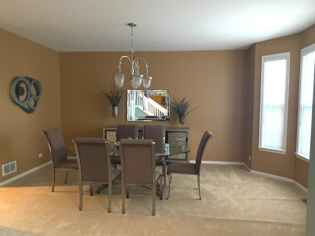 carpeted dining area featuring a notable chandelier