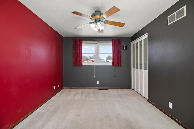 carpeted spare room with ceiling fan