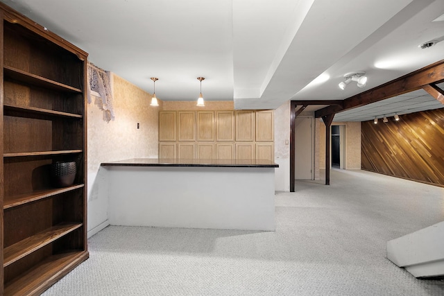 interior space featuring light colored carpet, wooden walls, light brown cabinetry, and pendant lighting