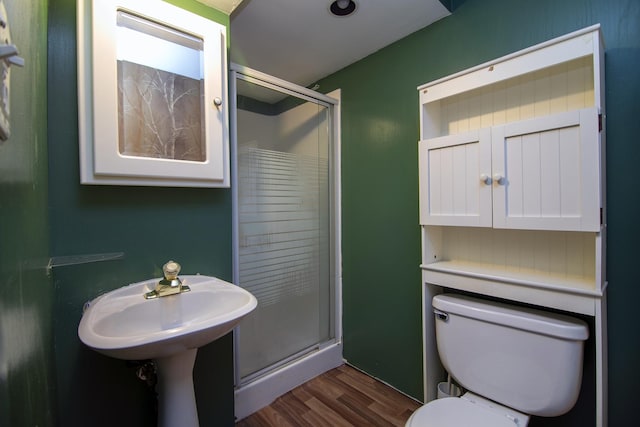 bathroom featuring hardwood / wood-style flooring, sink, toilet, and a shower with door