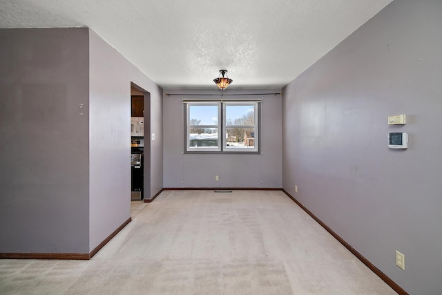 empty room with a textured ceiling and light colored carpet