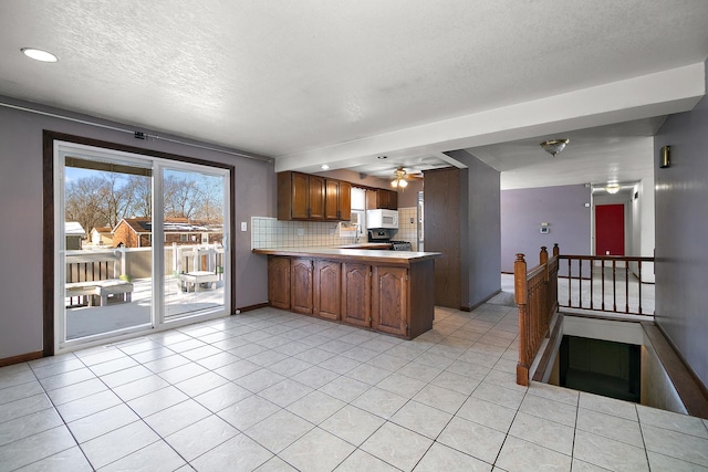 kitchen with backsplash, kitchen peninsula, a textured ceiling, and light tile patterned flooring