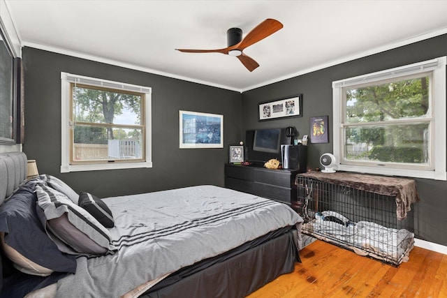 bedroom featuring hardwood / wood-style floors, ceiling fan, crown molding, and multiple windows