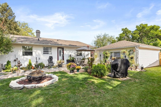 back of house featuring a lawn, a patio, and a fire pit