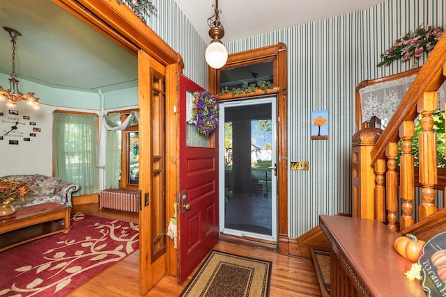 foyer with light hardwood / wood-style flooring, a notable chandelier, and radiator