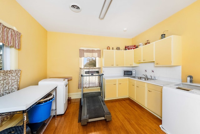 kitchen with washer / dryer, cream cabinets, sink, and light wood-type flooring