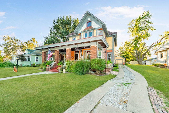 view of front of home with an outdoor structure, ceiling fan, a front lawn, and a porch