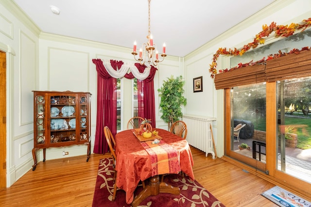 dining space featuring light hardwood / wood-style floors, crown molding, a chandelier, and radiator