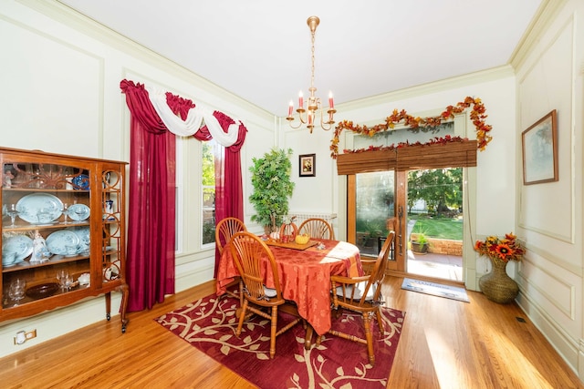 dining space with ornamental molding, an inviting chandelier, and hardwood / wood-style floors