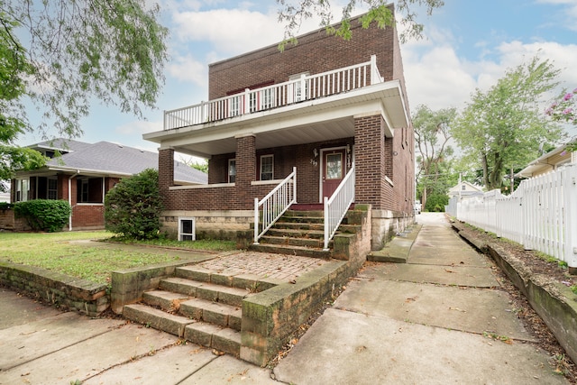 view of front facade with a balcony and a front lawn